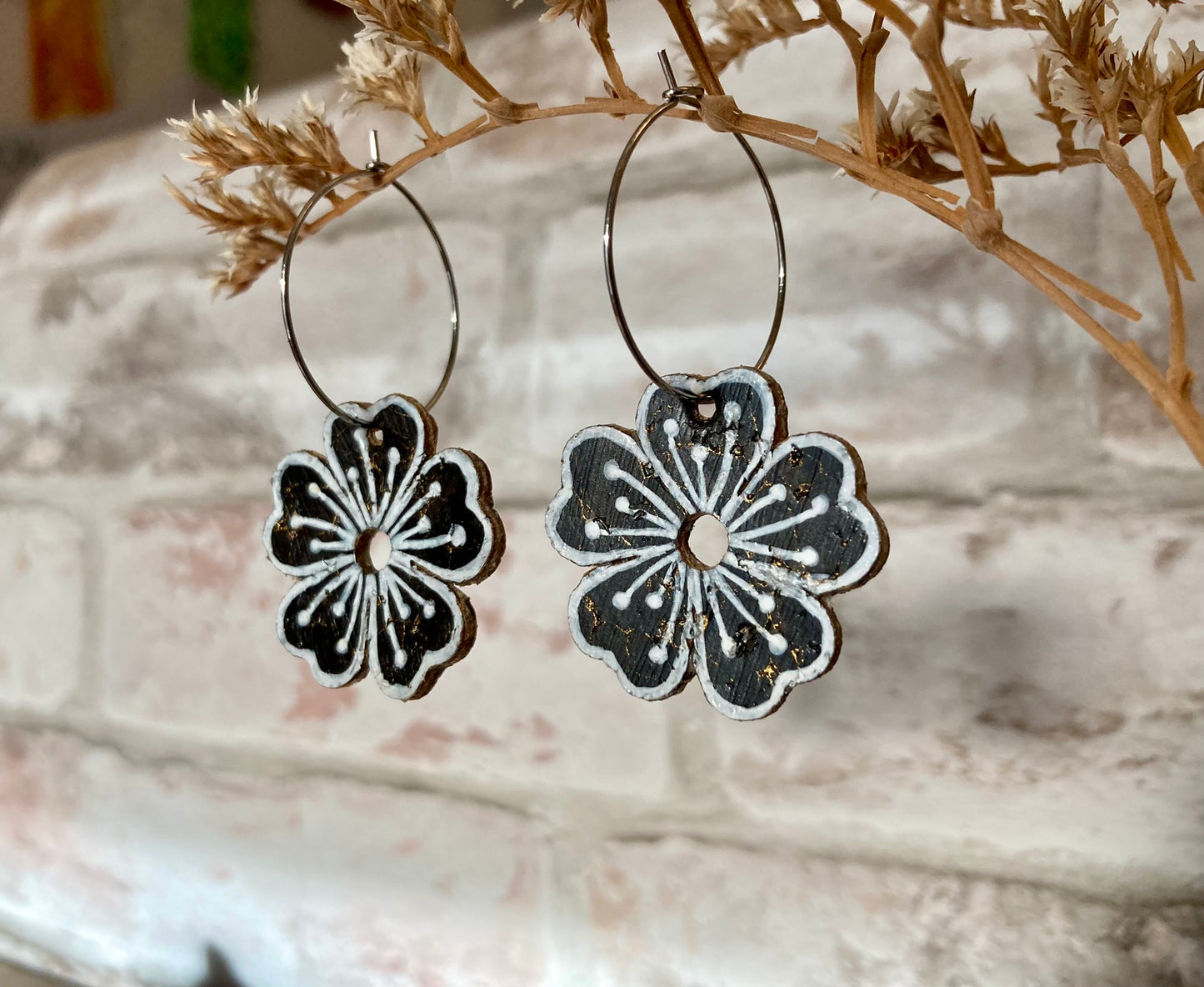 Black flower earrings hanging from branch