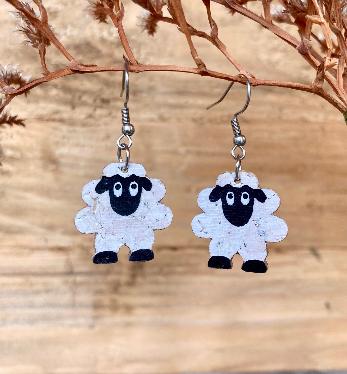 Sheep-shaped earrings on a wooden background