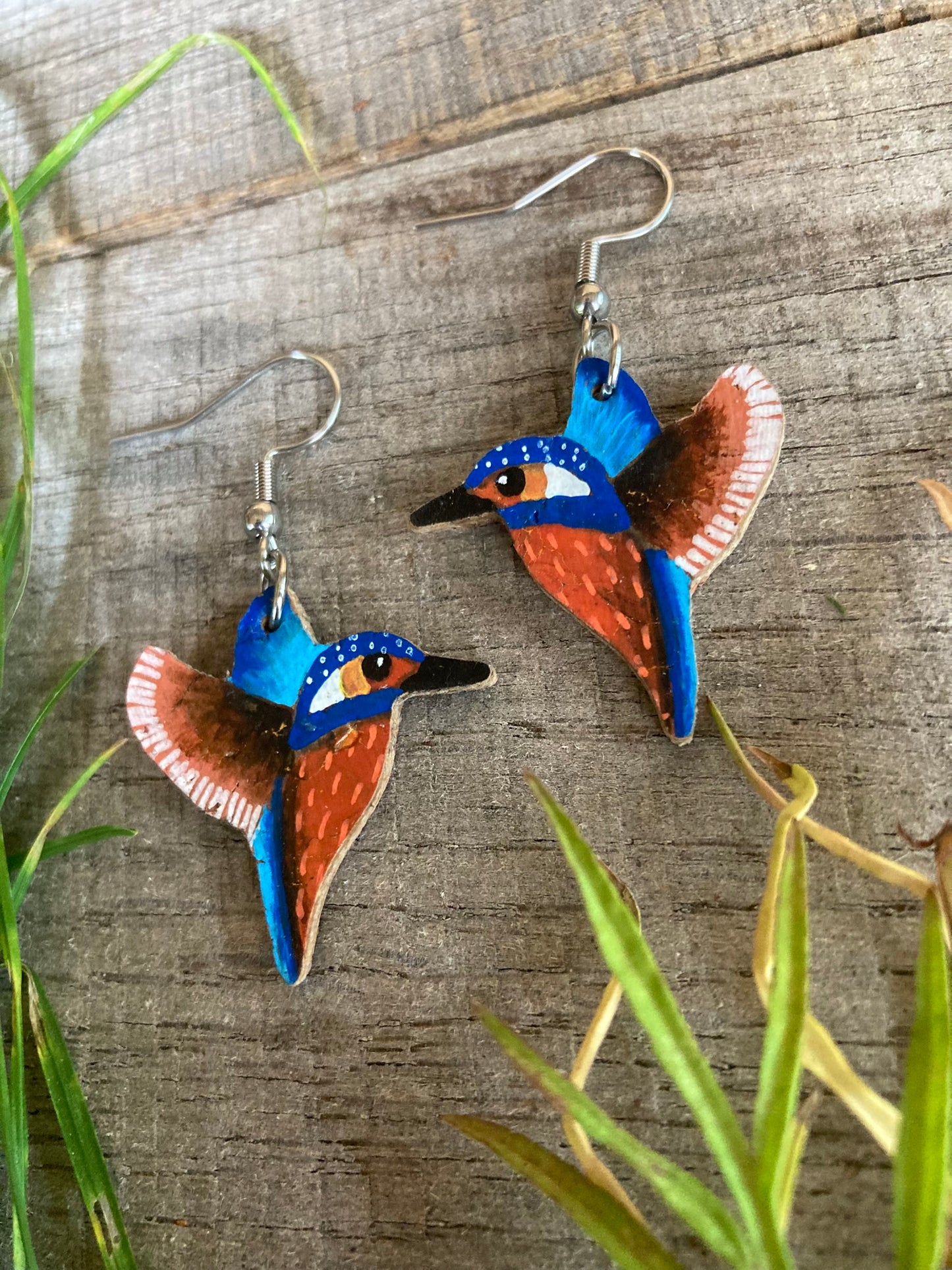Kingfisher earrings on a wooden surface with grass