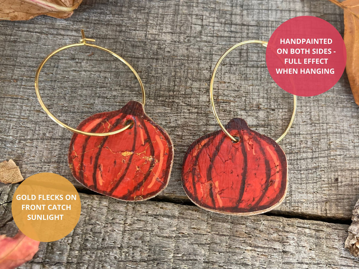 Pumpkin cork earrings on gold hoops with text highlighting the double-sided handpainted design and gold flecks that catch sunlight.