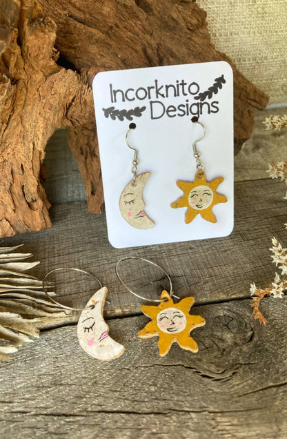 A pair of beautifully crafted Sun and Moon cork earrings, showcasing celestial charm and eco-friendly elegance. The earrings feature intricate details, capturing the harmonious balance of day and night in a sustainable design