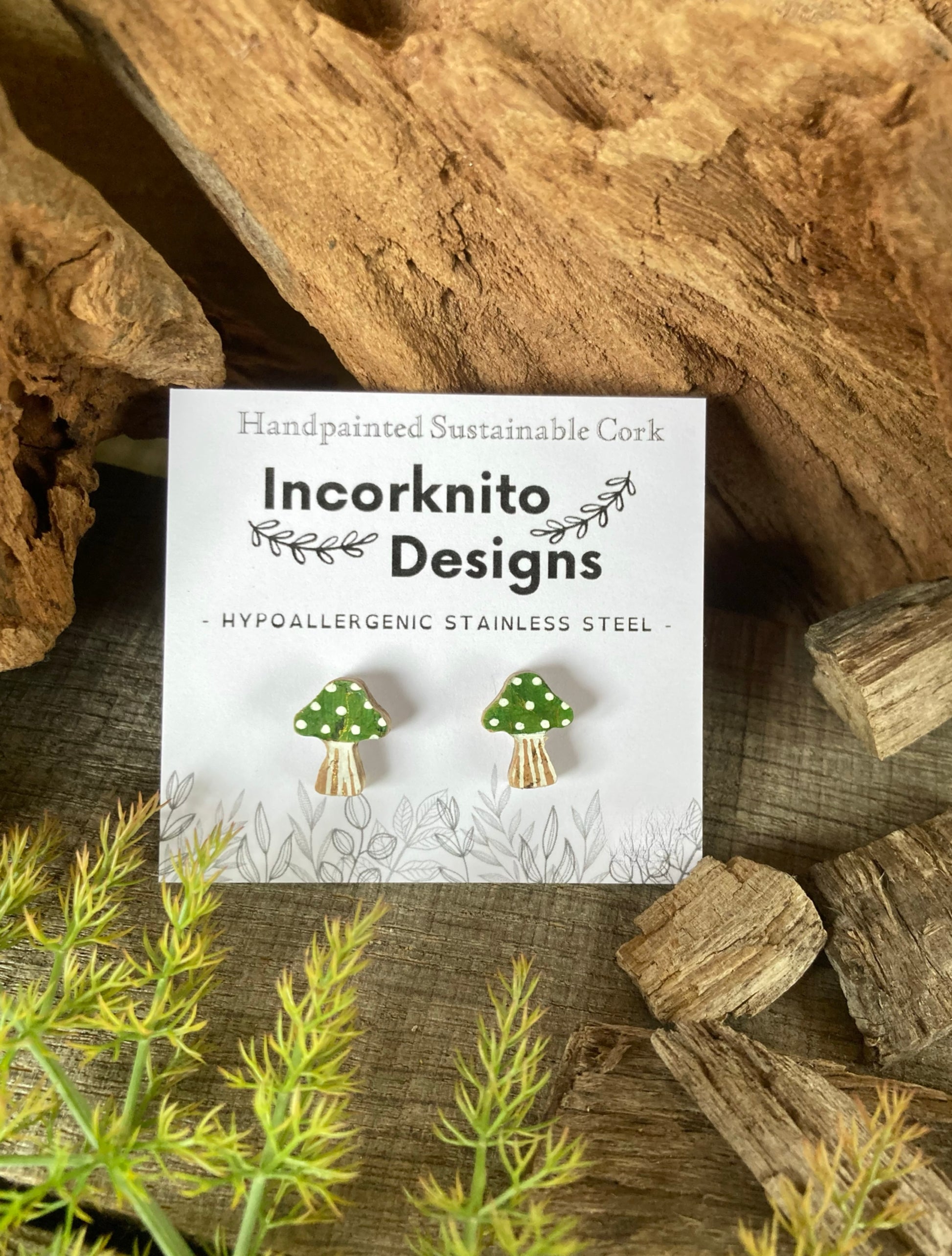 Incorknito Designs green toadstool earrings on a card with natural background