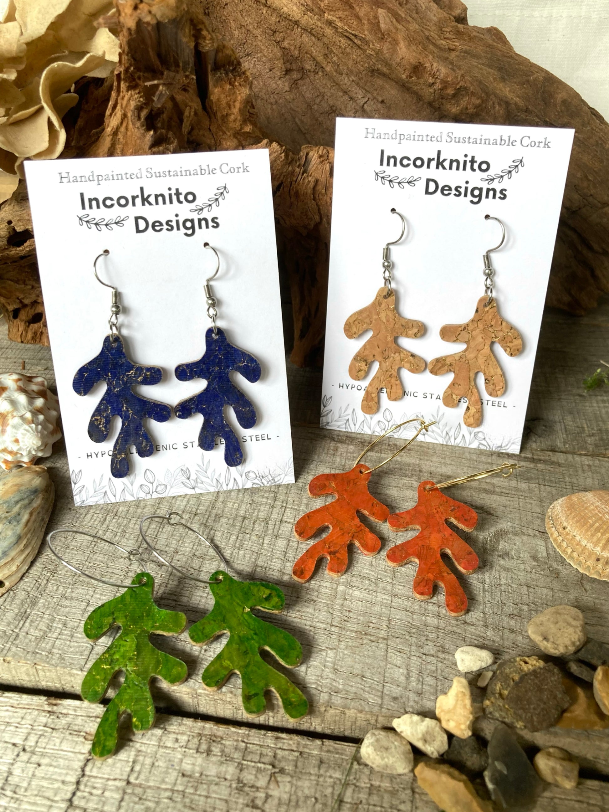 Set of four cork coral shaped earrings on Incorknito Designs cards against a natural wood background.