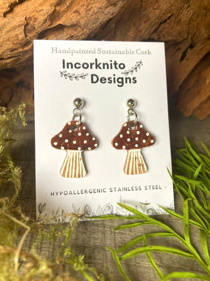 Brown mushroom-shaped earrings on a card with 'Incorknito Designs' branding, set against a natural background.