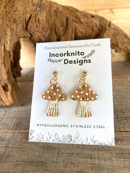 Mushroom-shaped earrings on a card with 'Incorknito Designs' branding, displayed against a wooden background.