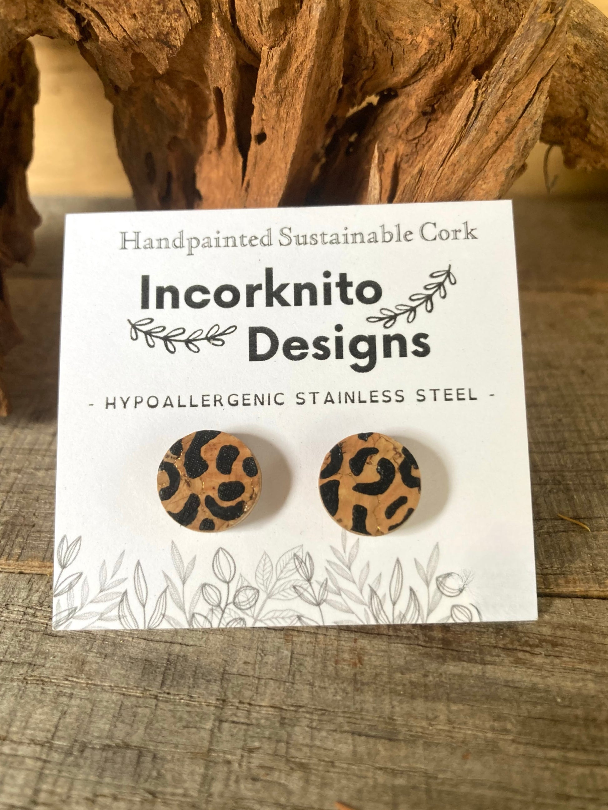Pair of leopard print earrings on a 'Incorknito Designs' card with cork background