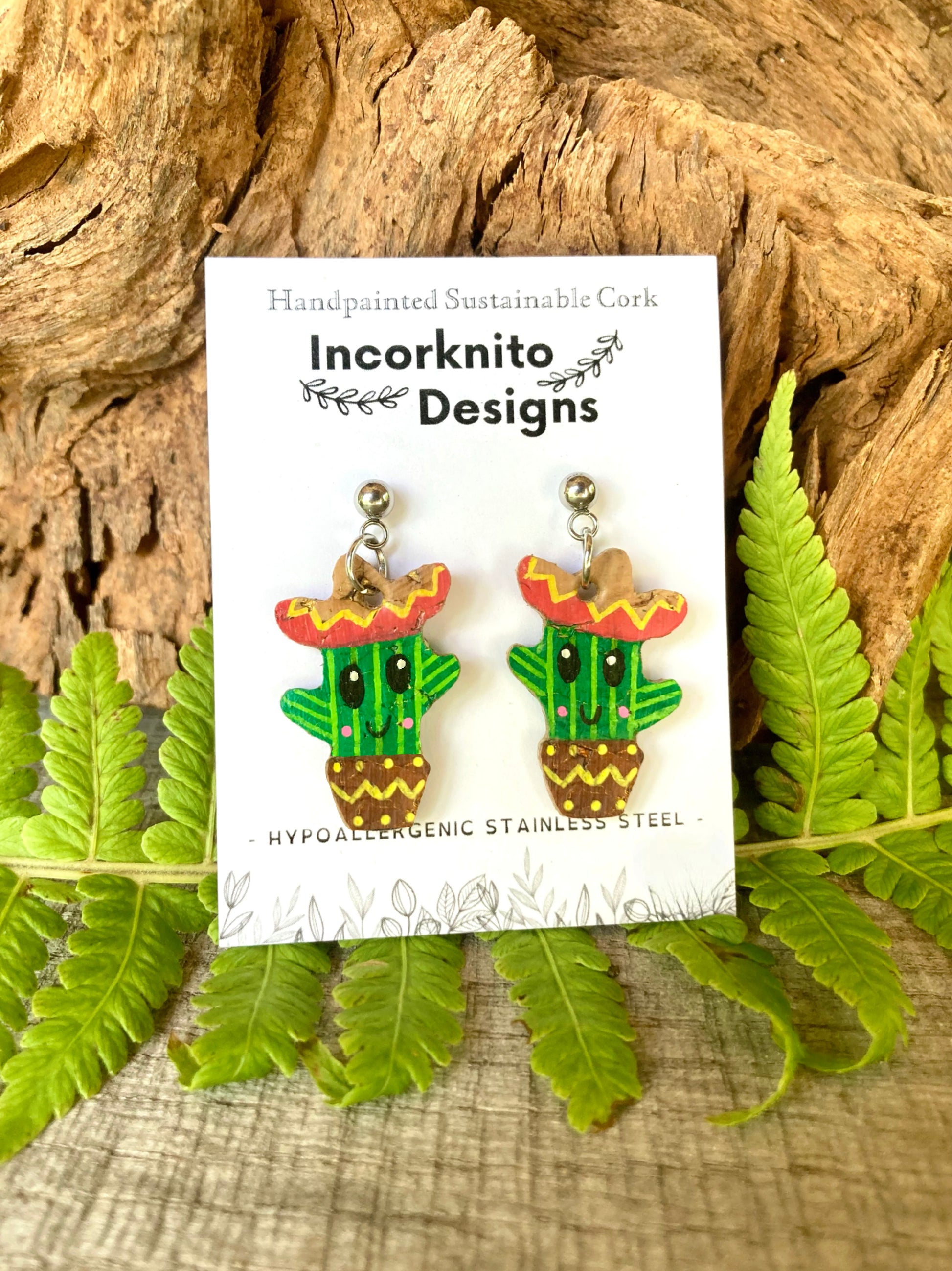 Cactus earrings with sombreros on a card labeled 'Incorknito Designs' against a natural background.
