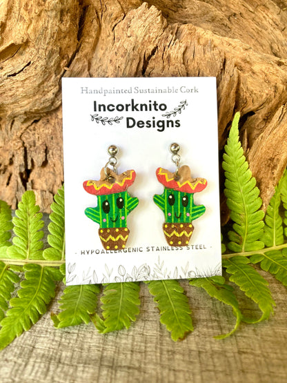 Cactus earrings with sombreros on a card labeled 'Incorknito Designs' against a natural background.