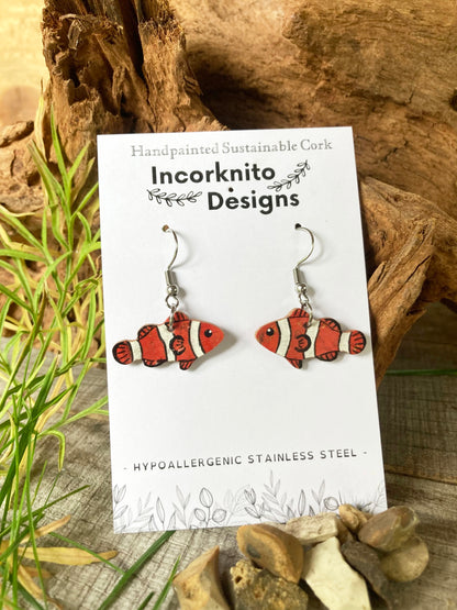 Cork earrings with clownfish design on a 'Incorknito Designs' card, placed on a natural wood background.