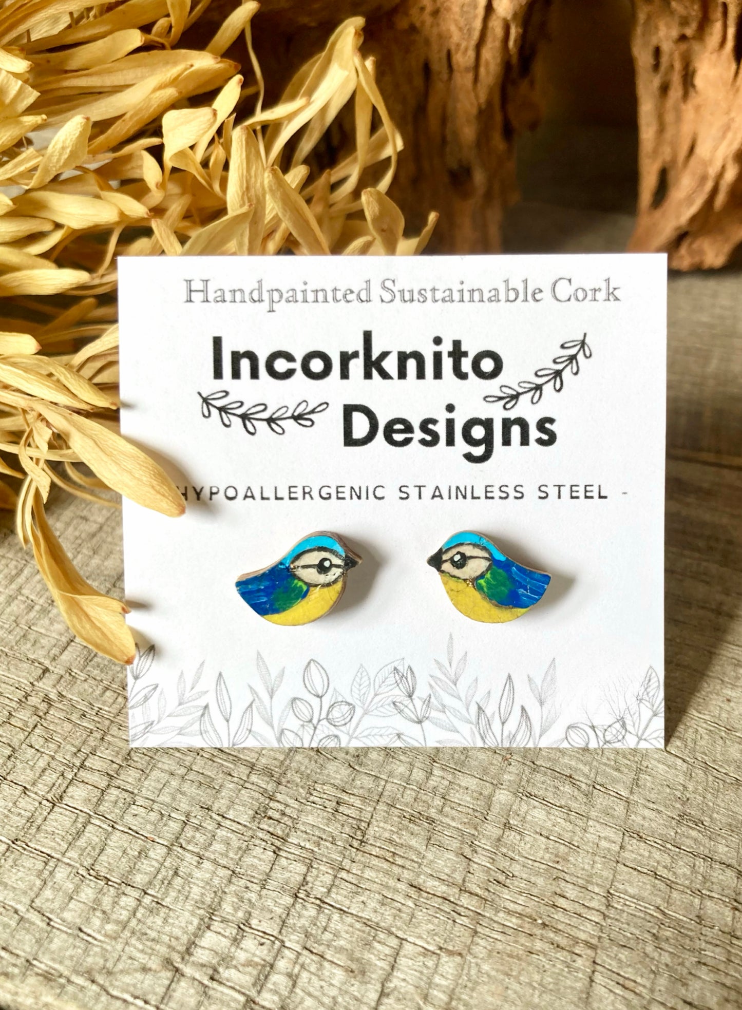 Blue tit earrings on a cork background with 'Incorknito Designs' label
