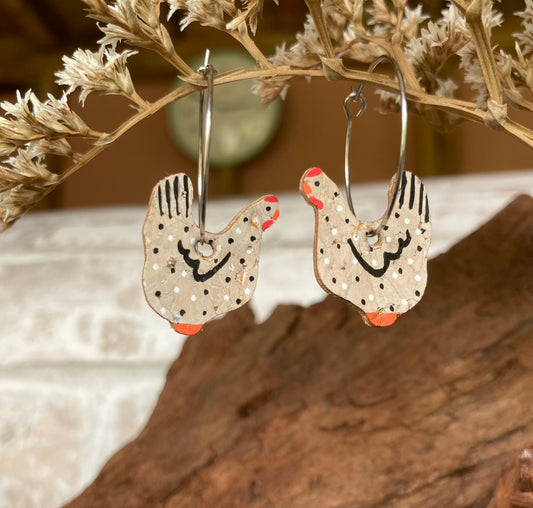 Black and white chicken cork earrings hanging from a branch