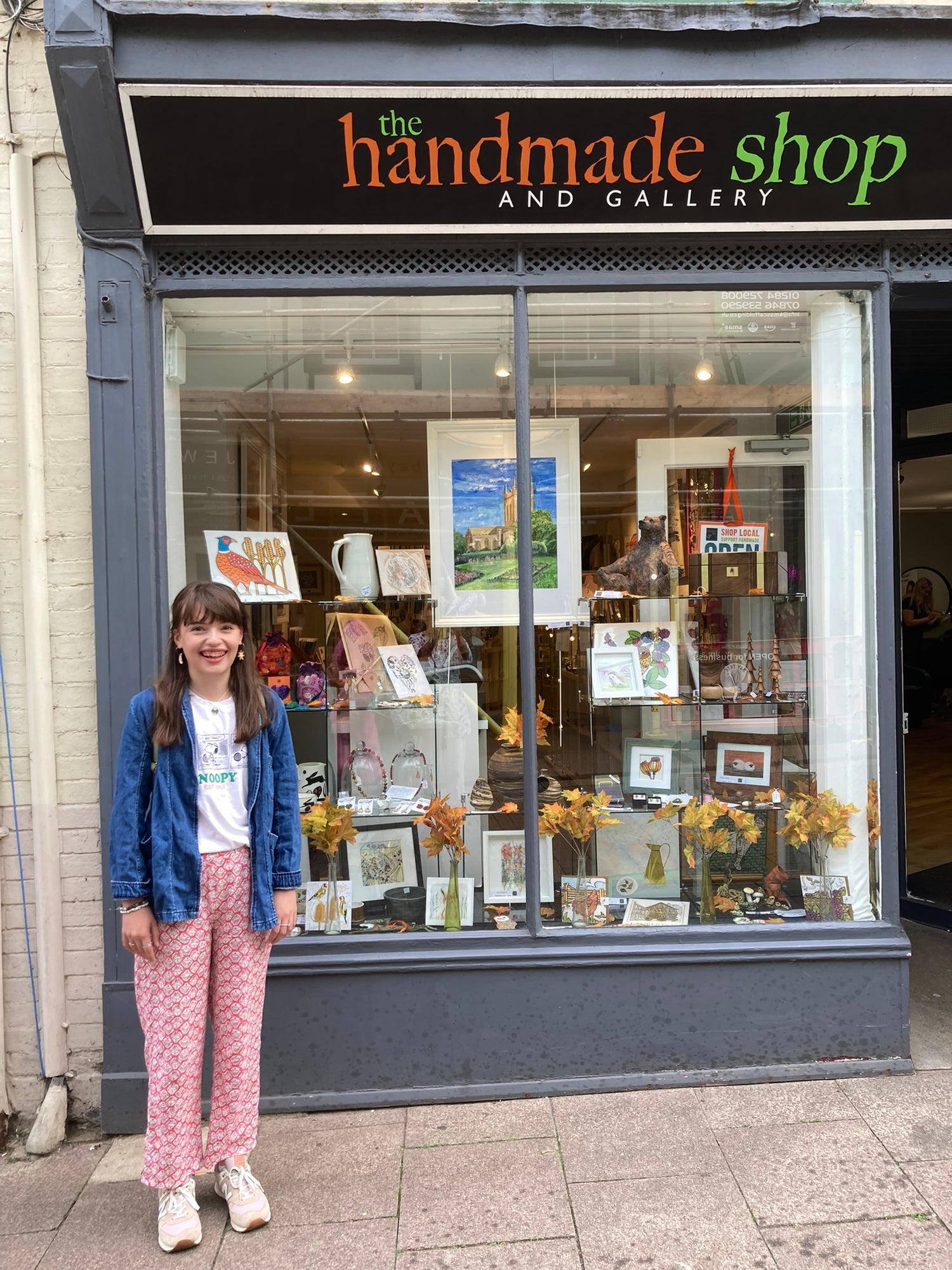 Young girl standing in front of 'The Handmade Shop and Gallery' store.