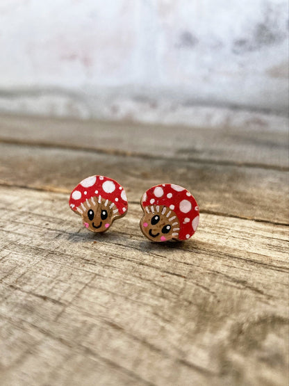 Happy face red mushroom earrings with white polka dots on a wooden surface