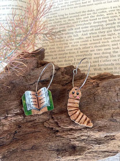 One book and one worm cork earrings on a wooden surface
