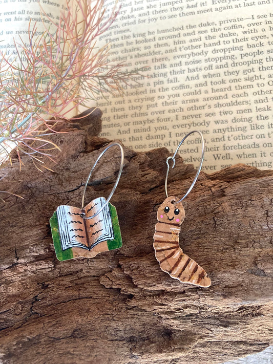 One book and one worm cork earrings on a wooden surface