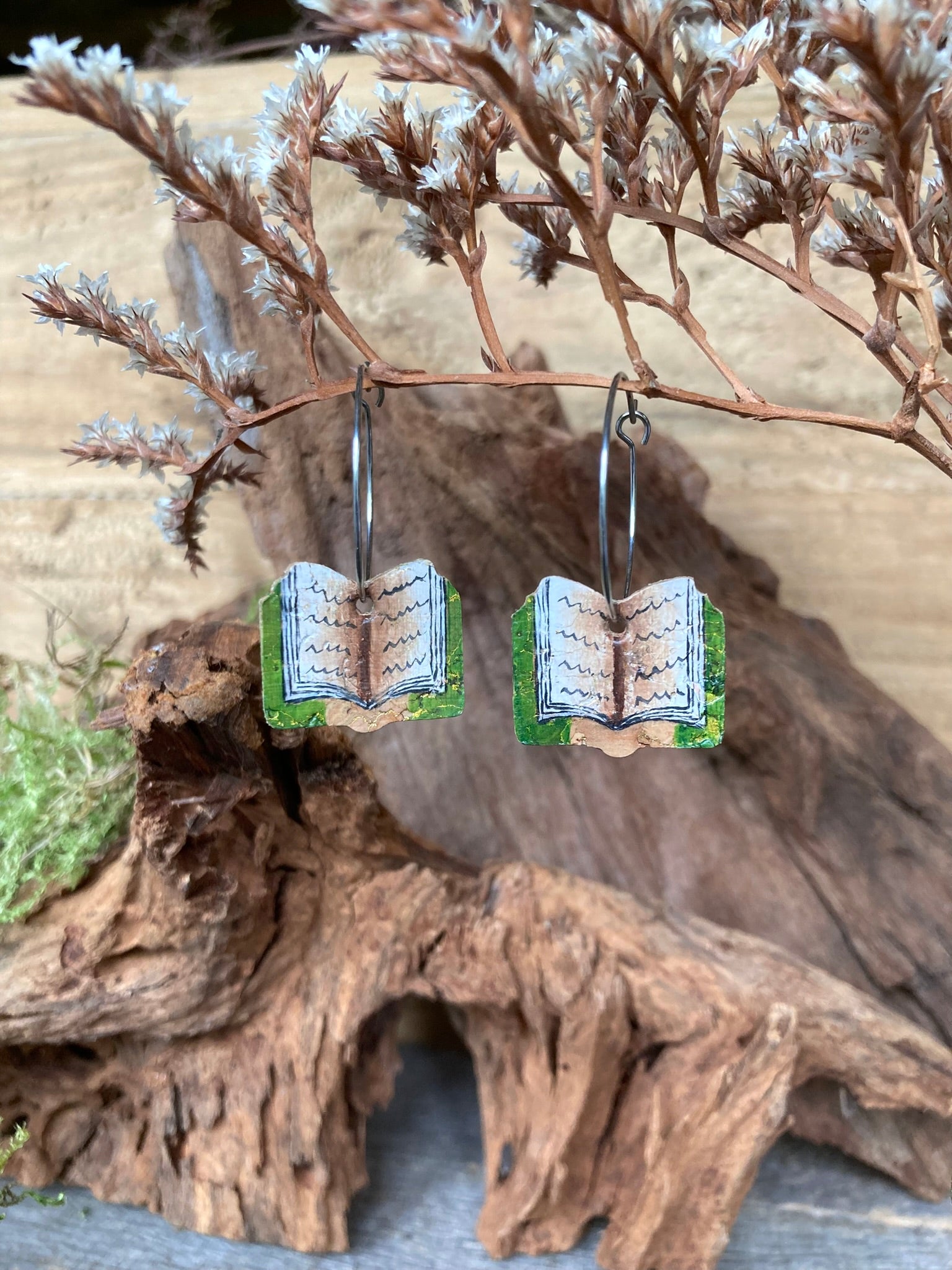 Book-themed earrings on a natural wooden background