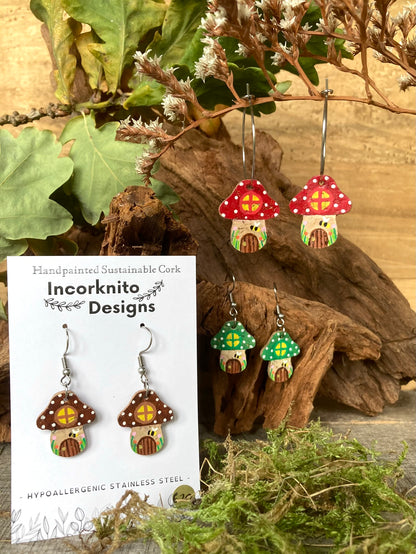 Fairy house-shaped earrings with 'Incorknito Designs' packaging on a natural wood and leaf background.