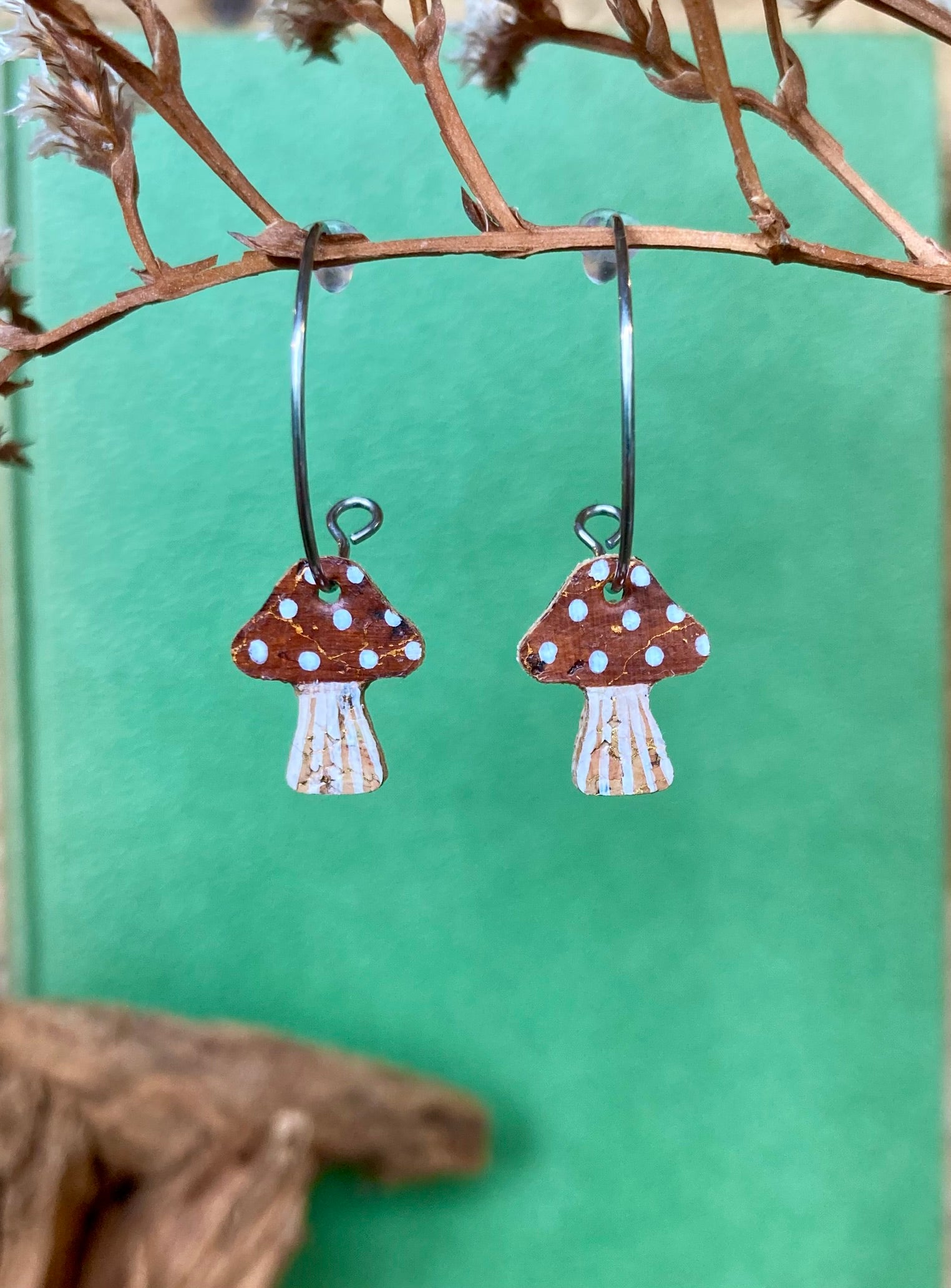 Mushroom-shaped earrings with polka dot design on a green background