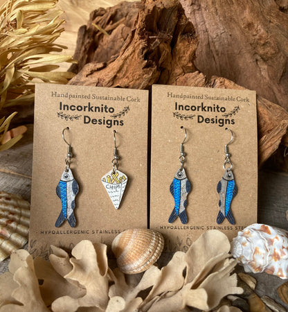 Pair of fish-shaped earrings and fish and chip painted earrings on Incorknito Designs cards with natural elements in the background