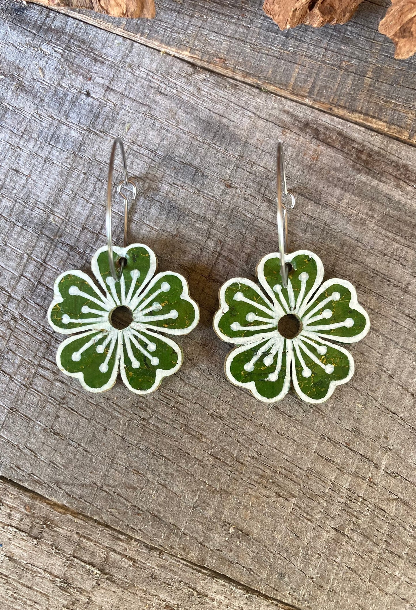 Green floral earrings on a wooden surface