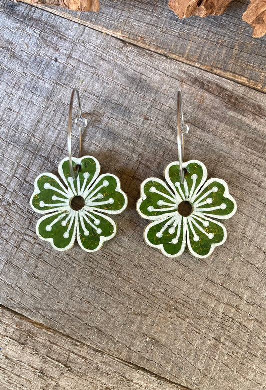 Green floral earrings on a wooden surface