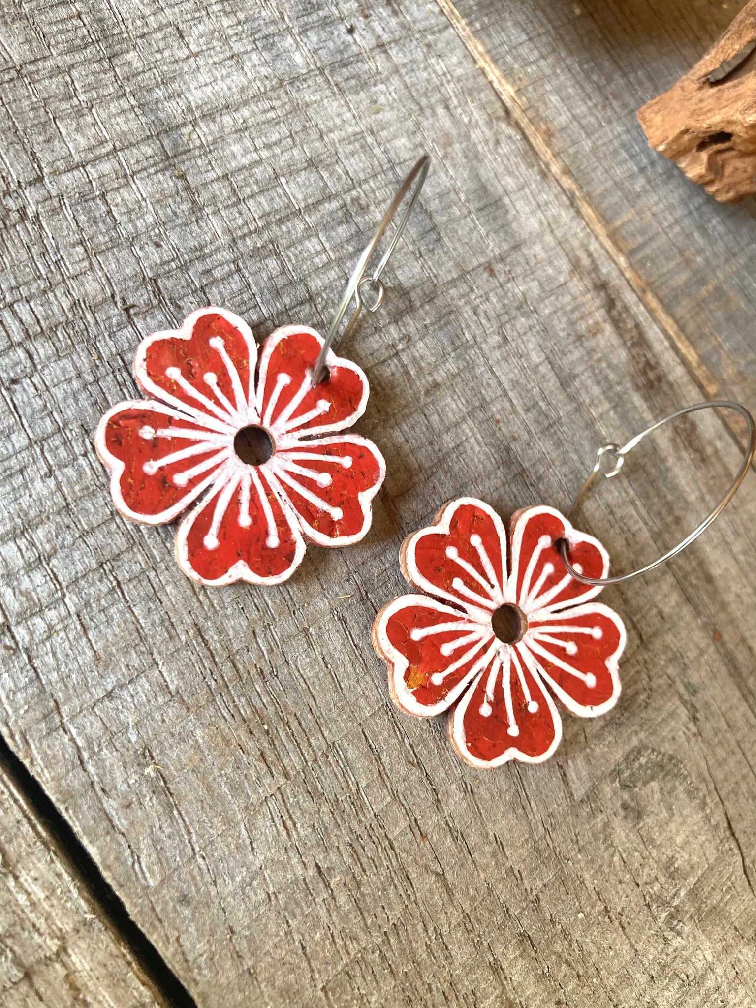Rust and white floral earrings on a wooden surface