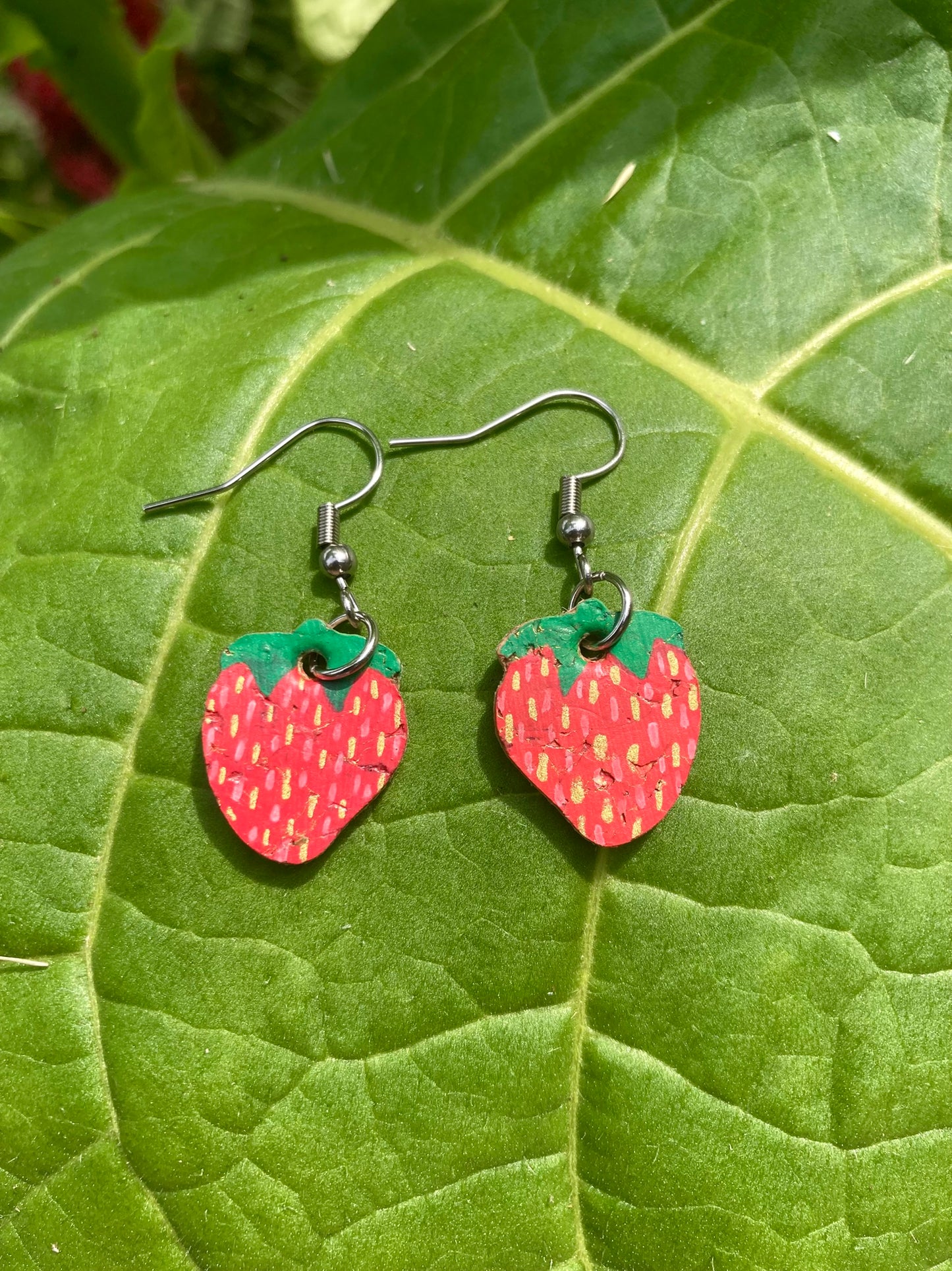 Strawberry-shaped earrings on a green leaf