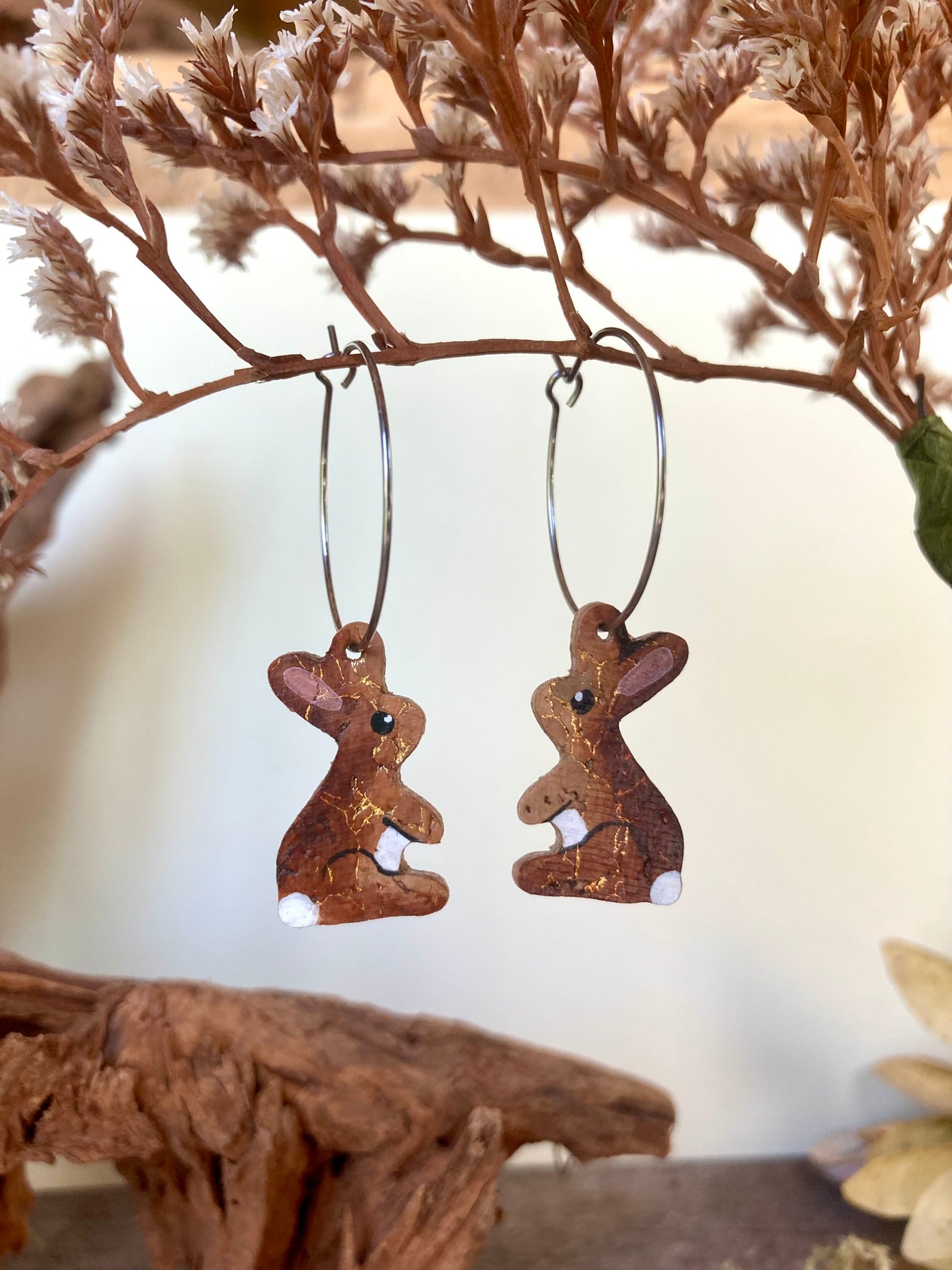 Pair of rabbit hoop earrings with white tail and tummy and pink ear hanging from branch
