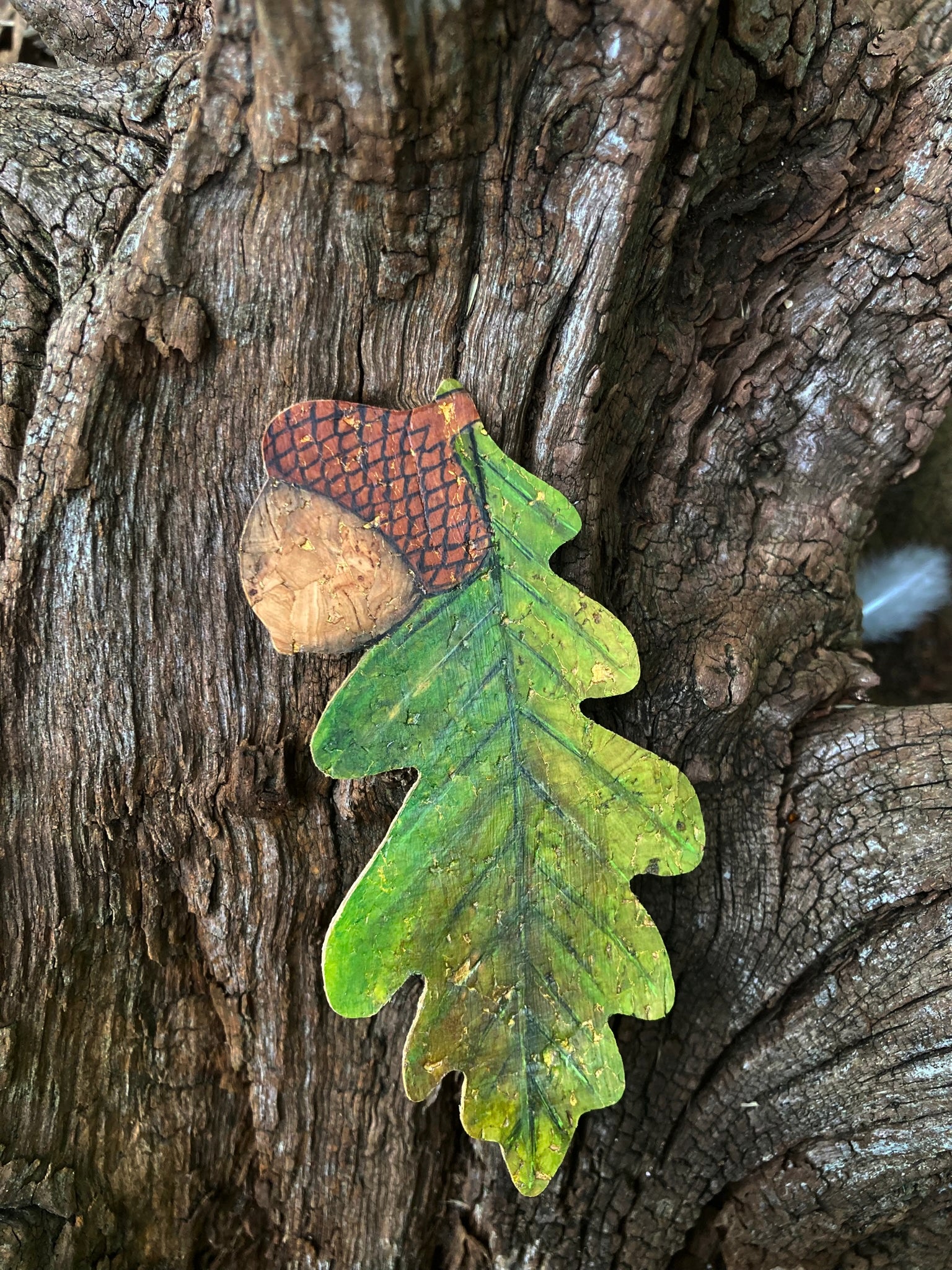 Decorative acorn and leaf bookmark on a tree trunk