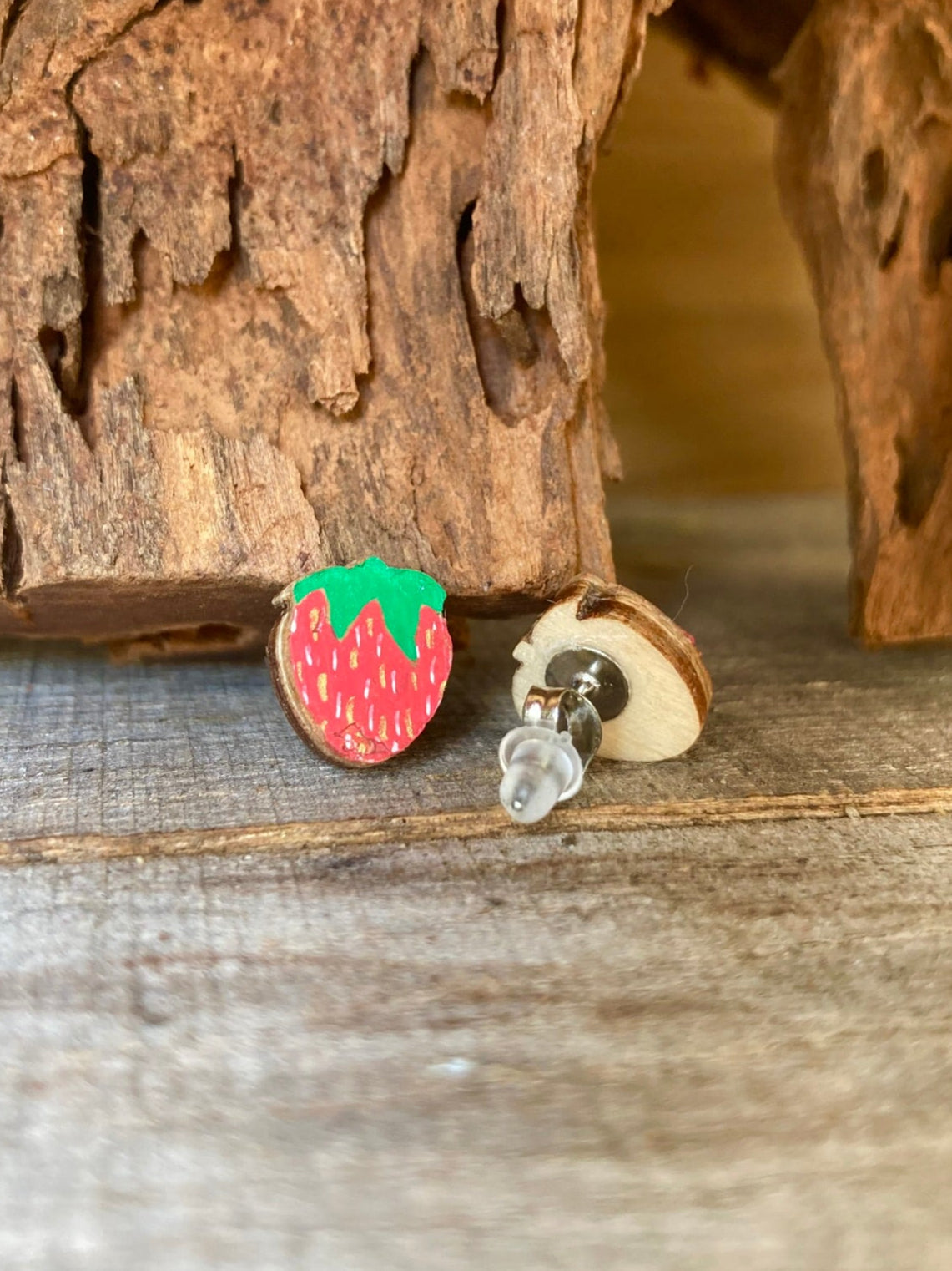 Strawberry stud earrings on a wooden surface