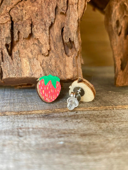 Strawberry stud earrings on a wooden surface