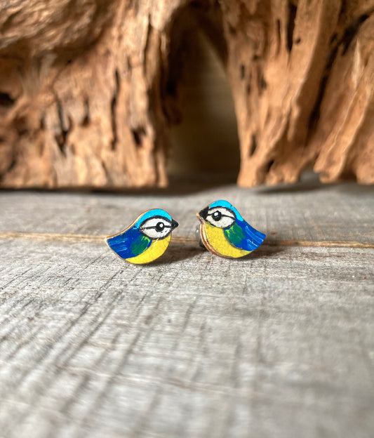 Colorful bird-shaped earrings on a wooden surface
