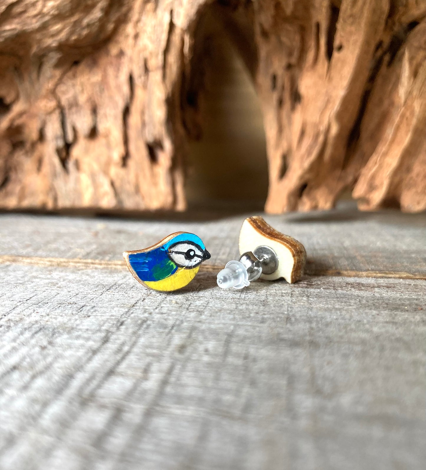 Blue tit earrings (yellow and blue) on a wooden surface with a natural background