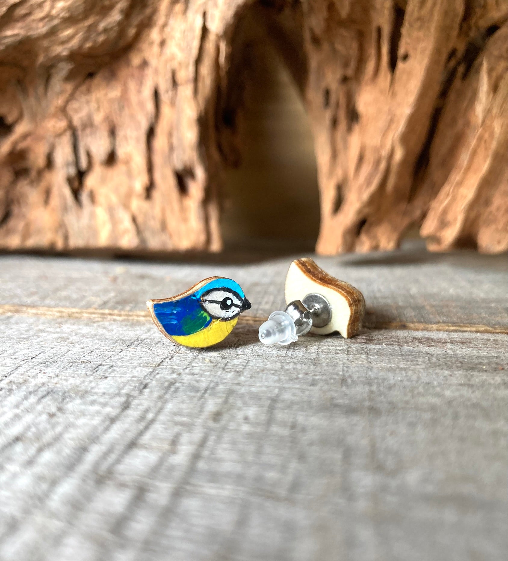 Blue tit earrings (yellow and blue) on a wooden surface with a natural background