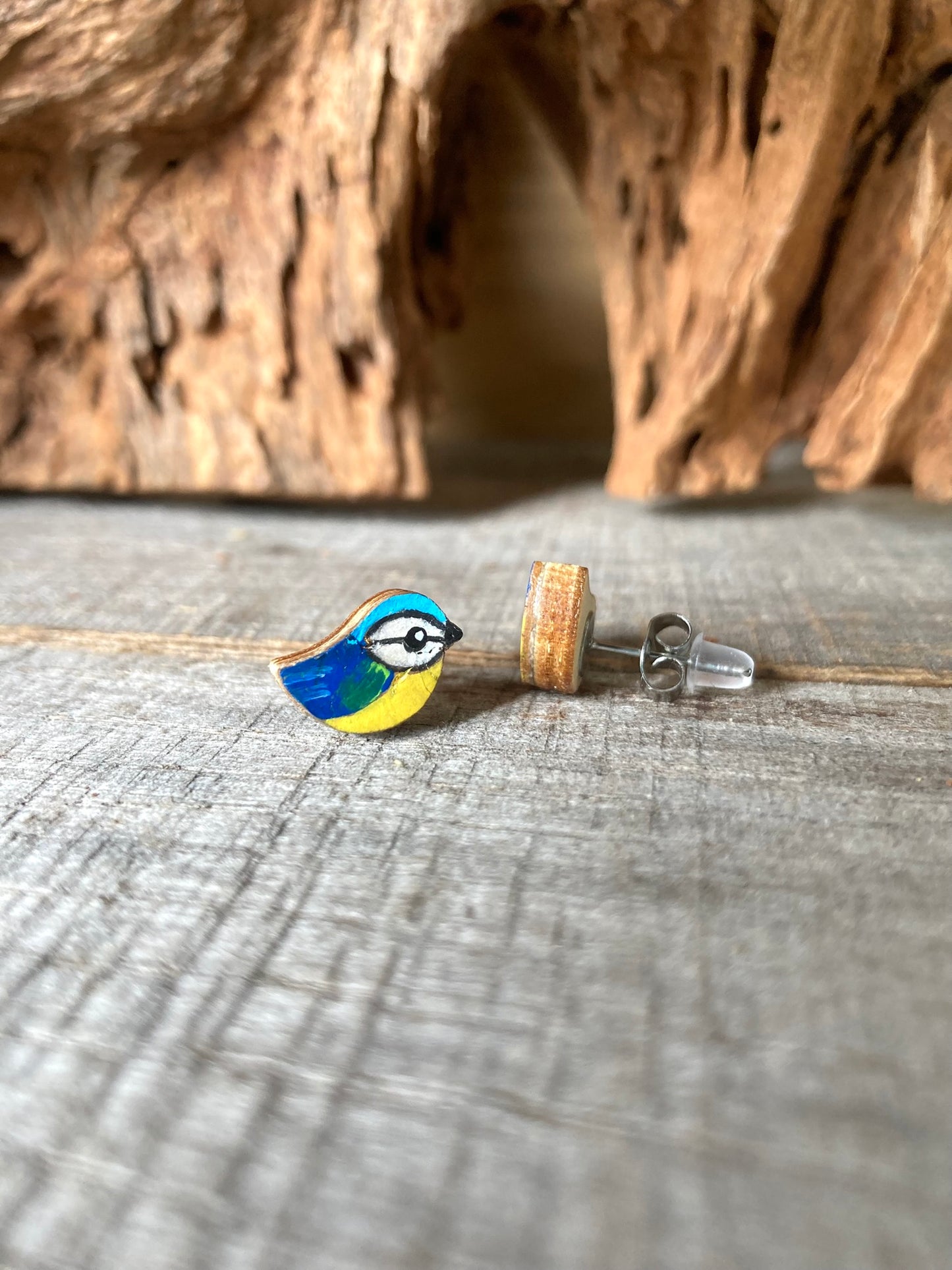 Bird-shaped earrings on a wooden surface with a natural background. Secured with a metal butterfly back and rubber back