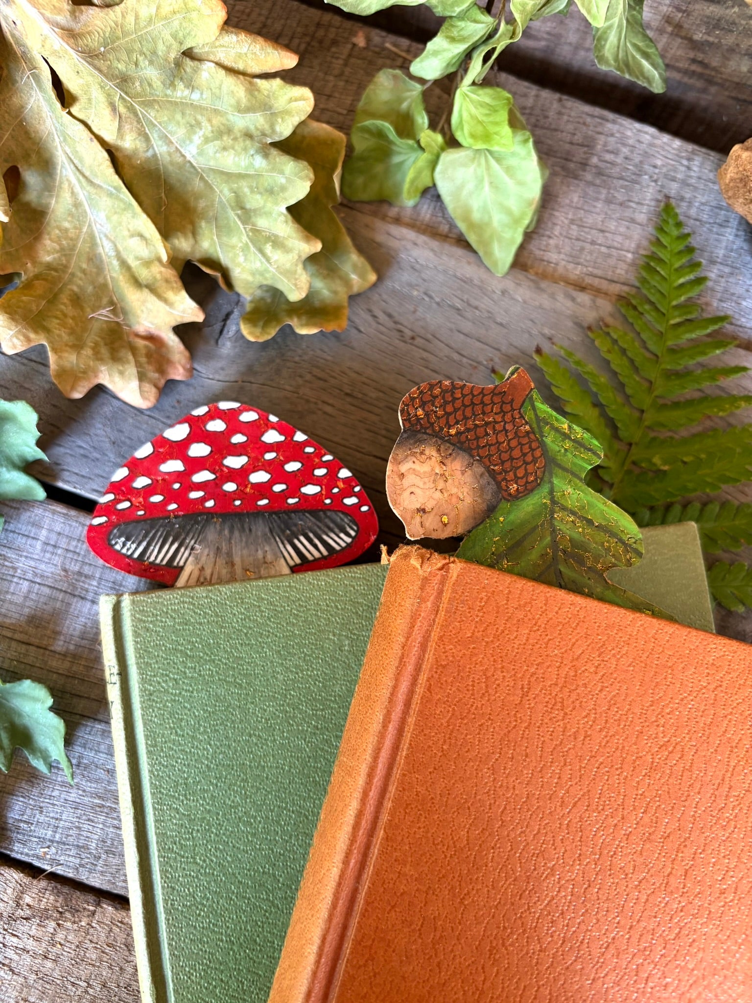 Acorn and oak leaf and toadstool cork bookmarks in green and orange hardback books with autumn oak leaves — handpainted sustainable cork bookmarks from Incorknito Designs