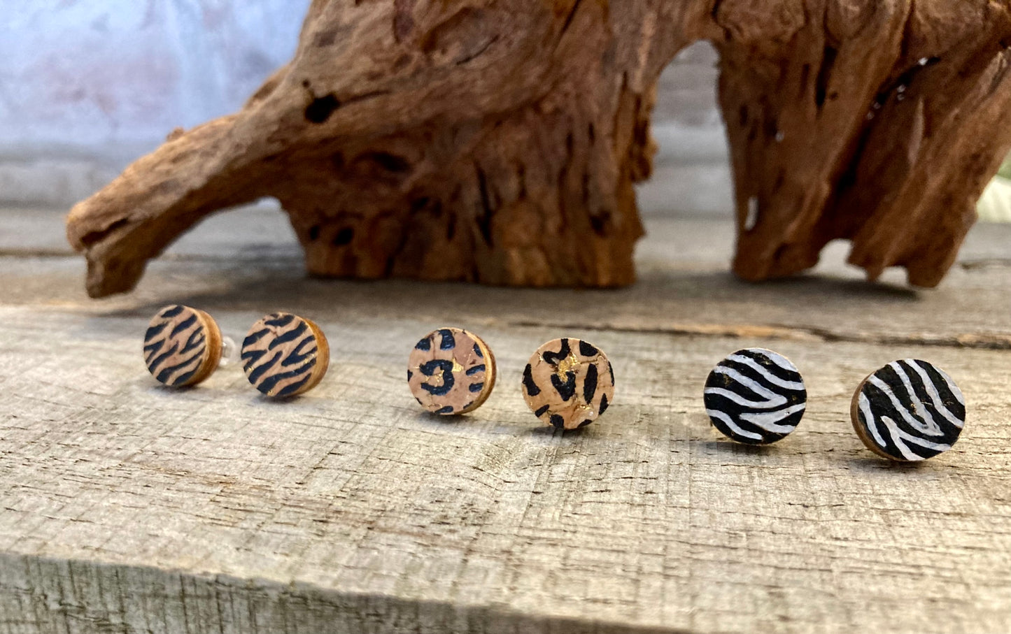 Animal print cork stud earrings — tiger, leopard and zebra print — on a driftwood surface