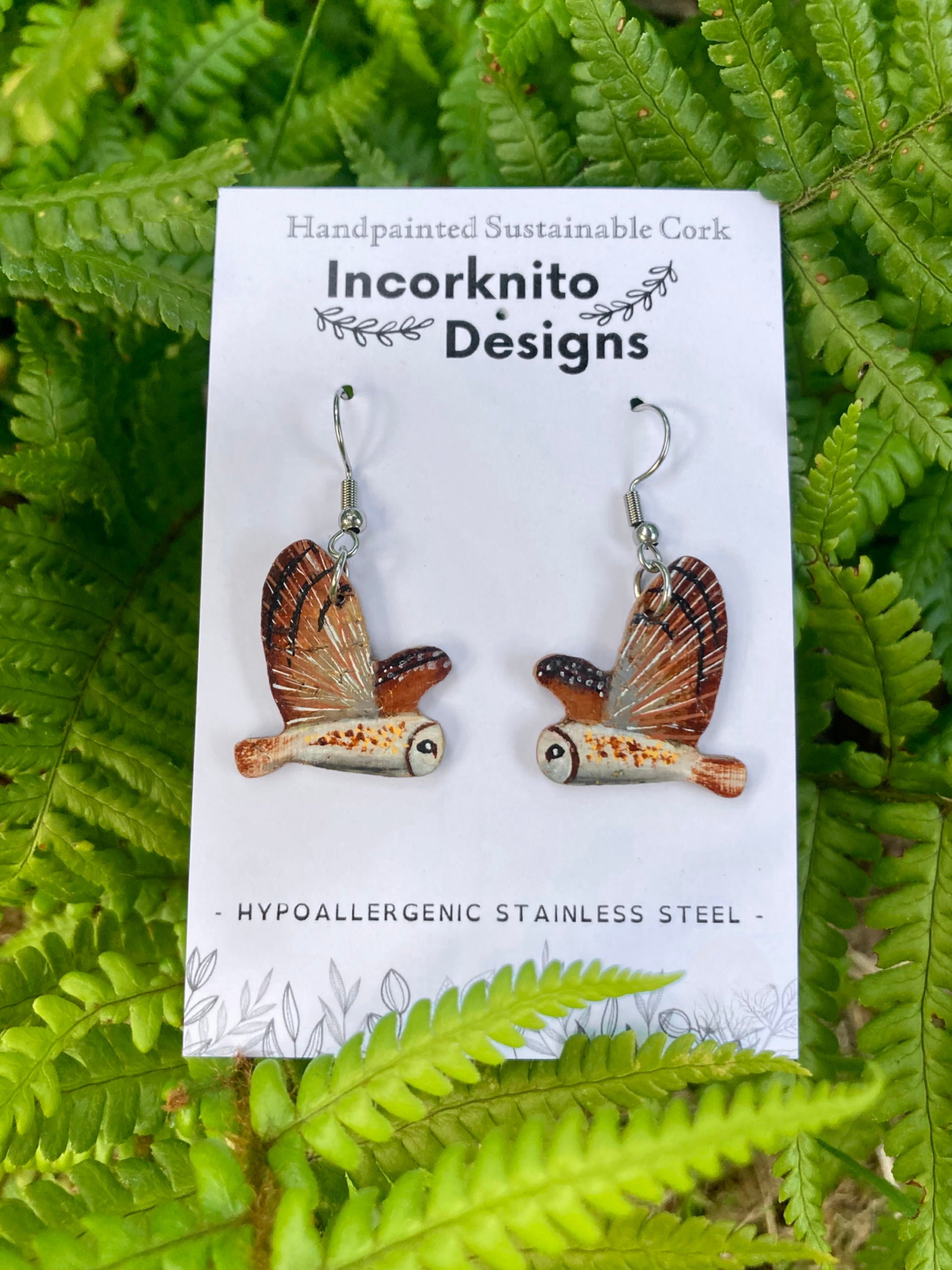 Barn owl cork earrings on silver hooks on Incorknito Designs card against green ferns — handpainted sustainable British wildlife jewellery