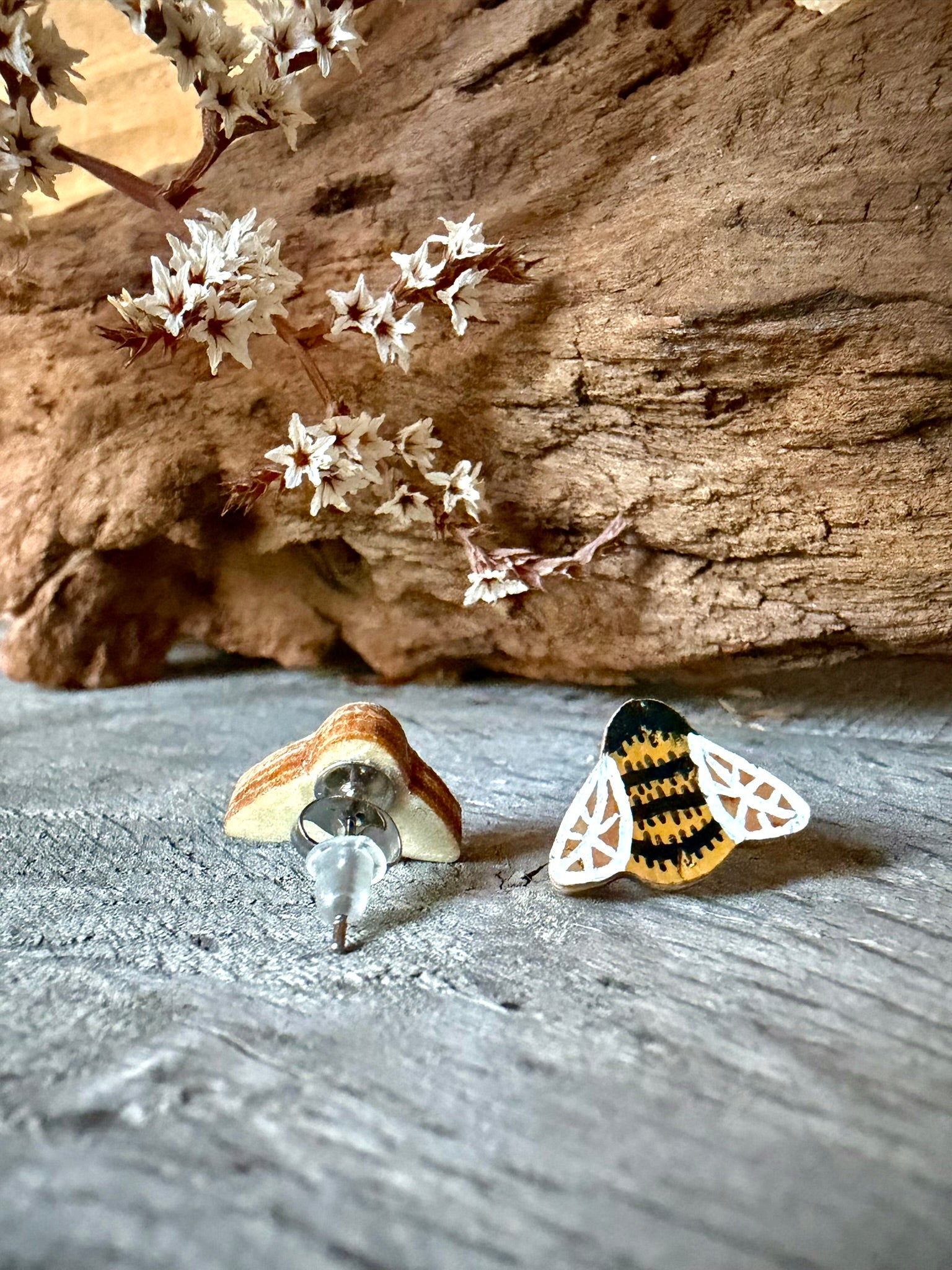 Front and reverse of a bee cork stud earring showing the natural gold fleck wood backing and stainless steel post with silicone back