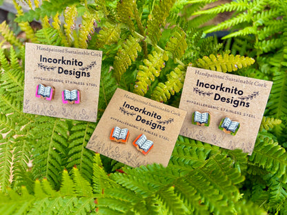 All three colour options of handpainted book cork stud earrings on Incorknito Designs kraft cards laid on green fern fronds