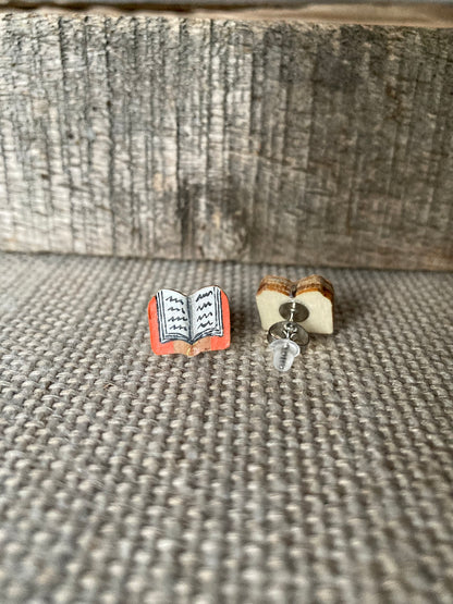 Handpainted book cork stud earrings on a linen surface against weathered wood showing detail of FSC wood back supplied with stainless steel butterfly back and silicone one