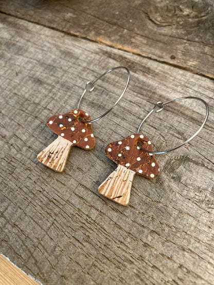 Brown toadstool cork large hoop earrings flat lay on plain weathered wood — editorial close-up showing the cork texture and gold fleck detail