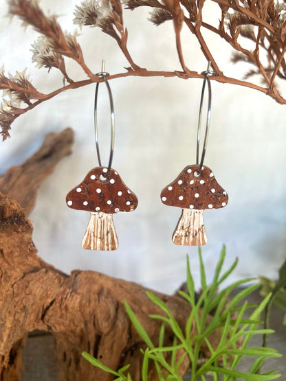 Brown toadstool cork large hoop earrings hanging from a dried branch — silver hoops with warm brown handpainted cap and white polka dots