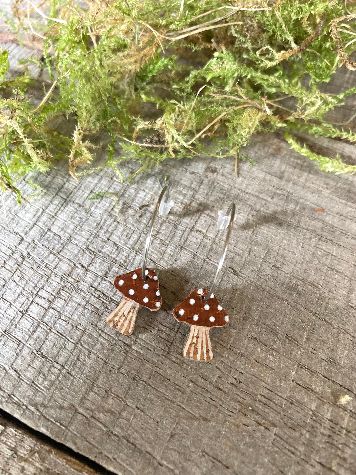 Brown toadstool cork mini hoop earrings on weathered wood with moss and greenery — handpainted sustainable jewellery 