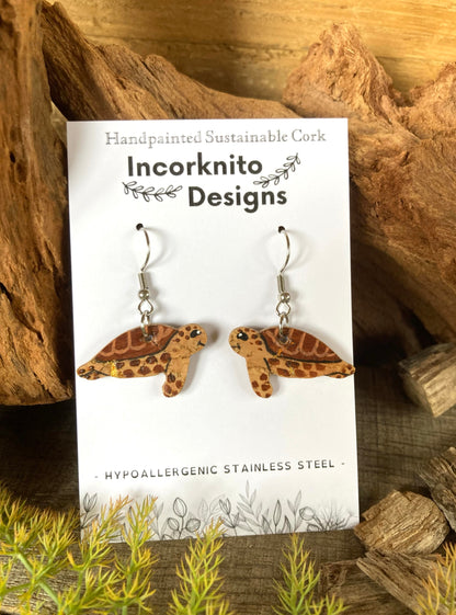 Brown turtle earrings on an Incorknito Designs branded card set against a natural wood background