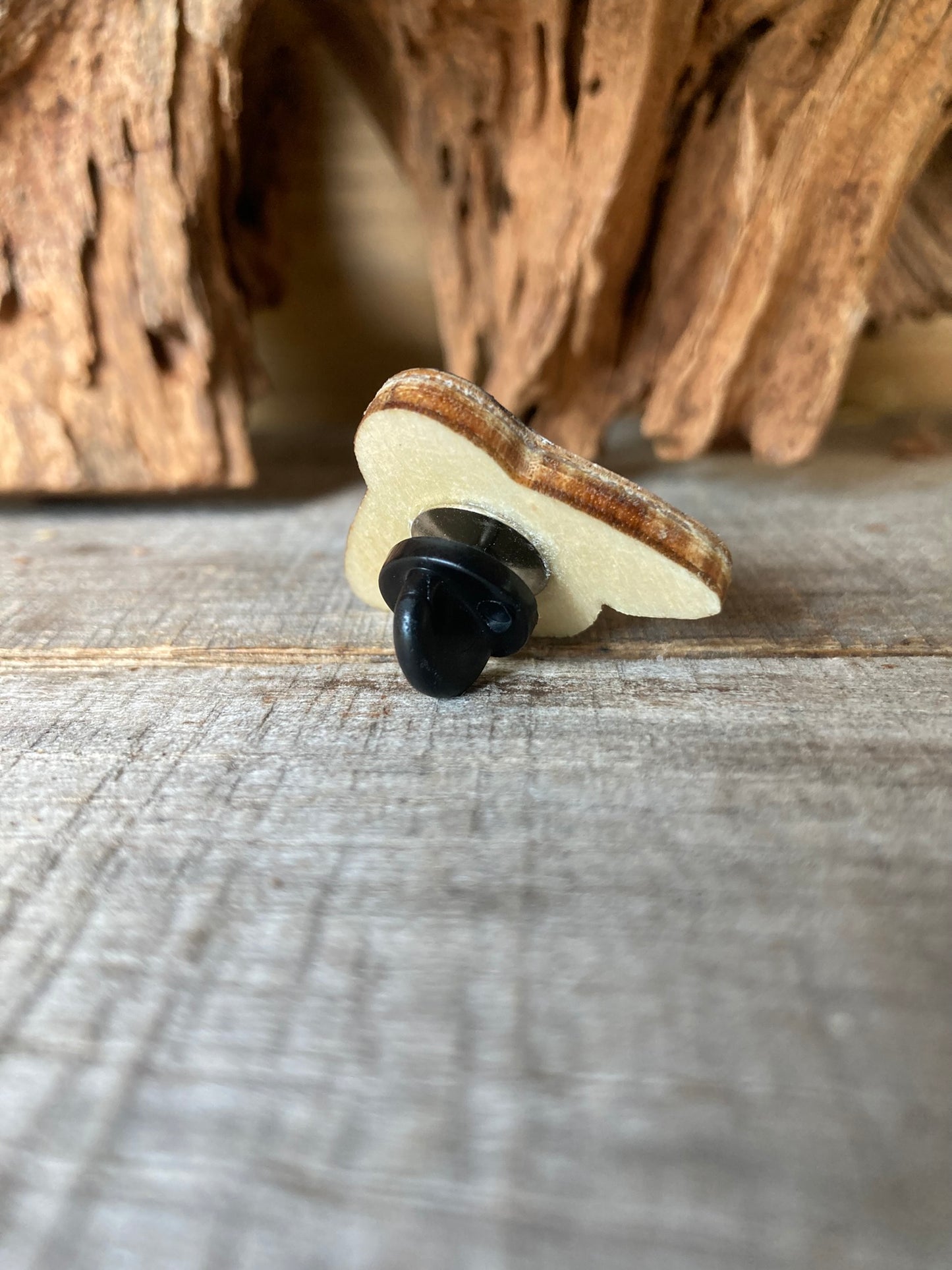 Side profile of the bumblebee cork pin badge on weathered wood showing FSC ply base layers and black rubber butterfly clasp