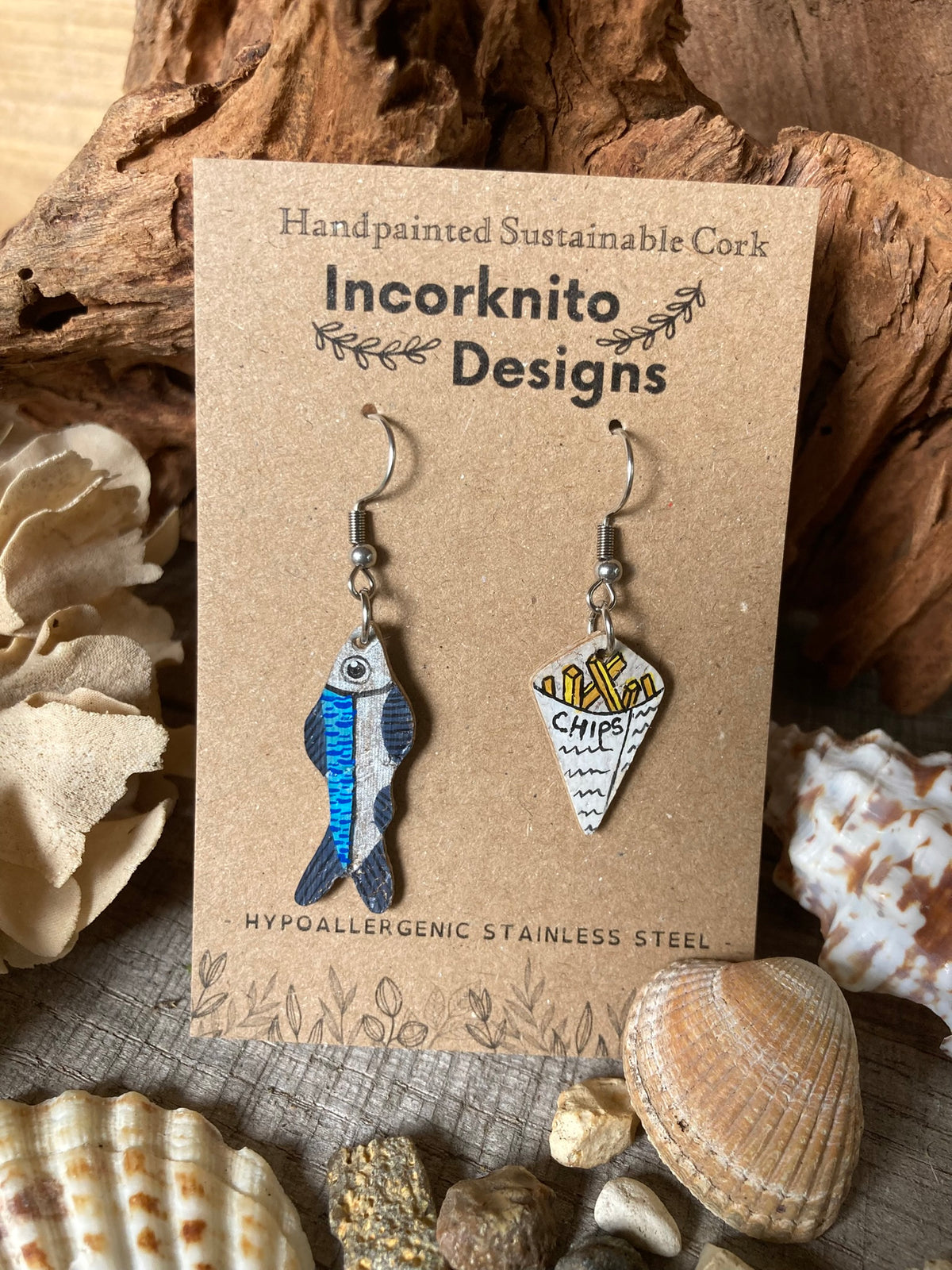 Handpainted fish and chips cork earrings displayed on an Incorknito Designs branded card with seashells and driftwood