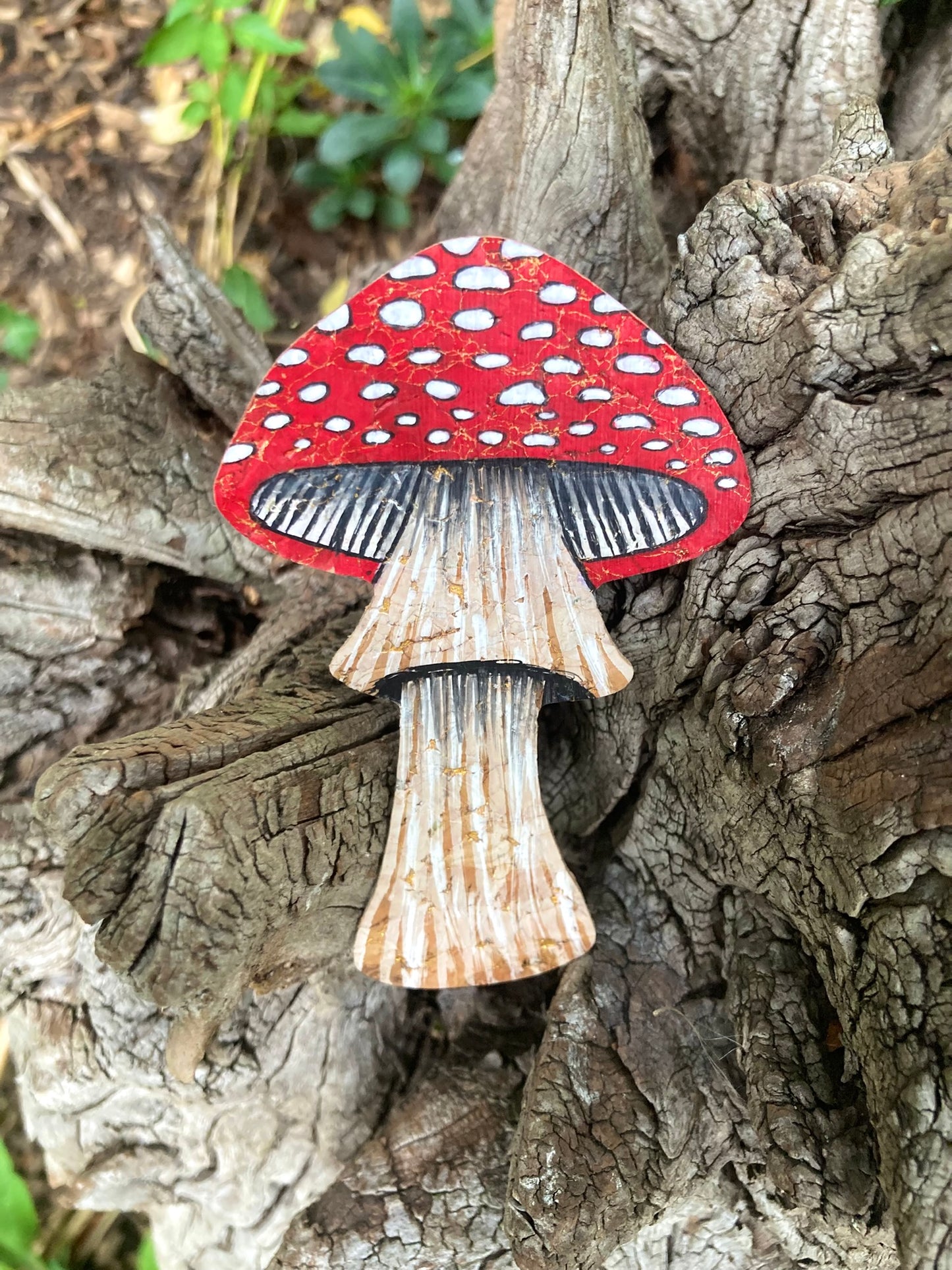 Handpainted fly agaric toadstool cork bookmark against gnarled tree bark — red cap with white spots and natural cork stem with painted texture