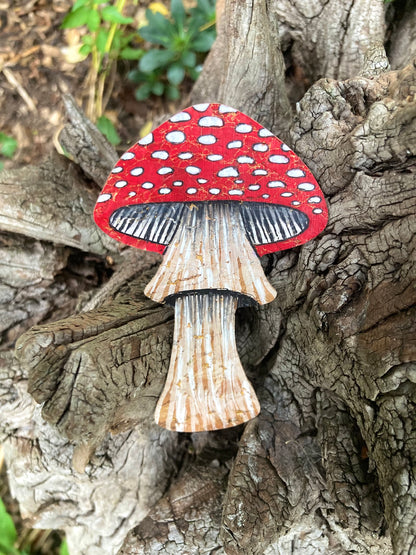 Handpainted fly agaric toadstool cork bookmark against gnarled tree bark — red cap with white spots and natural cork stem with painted texture