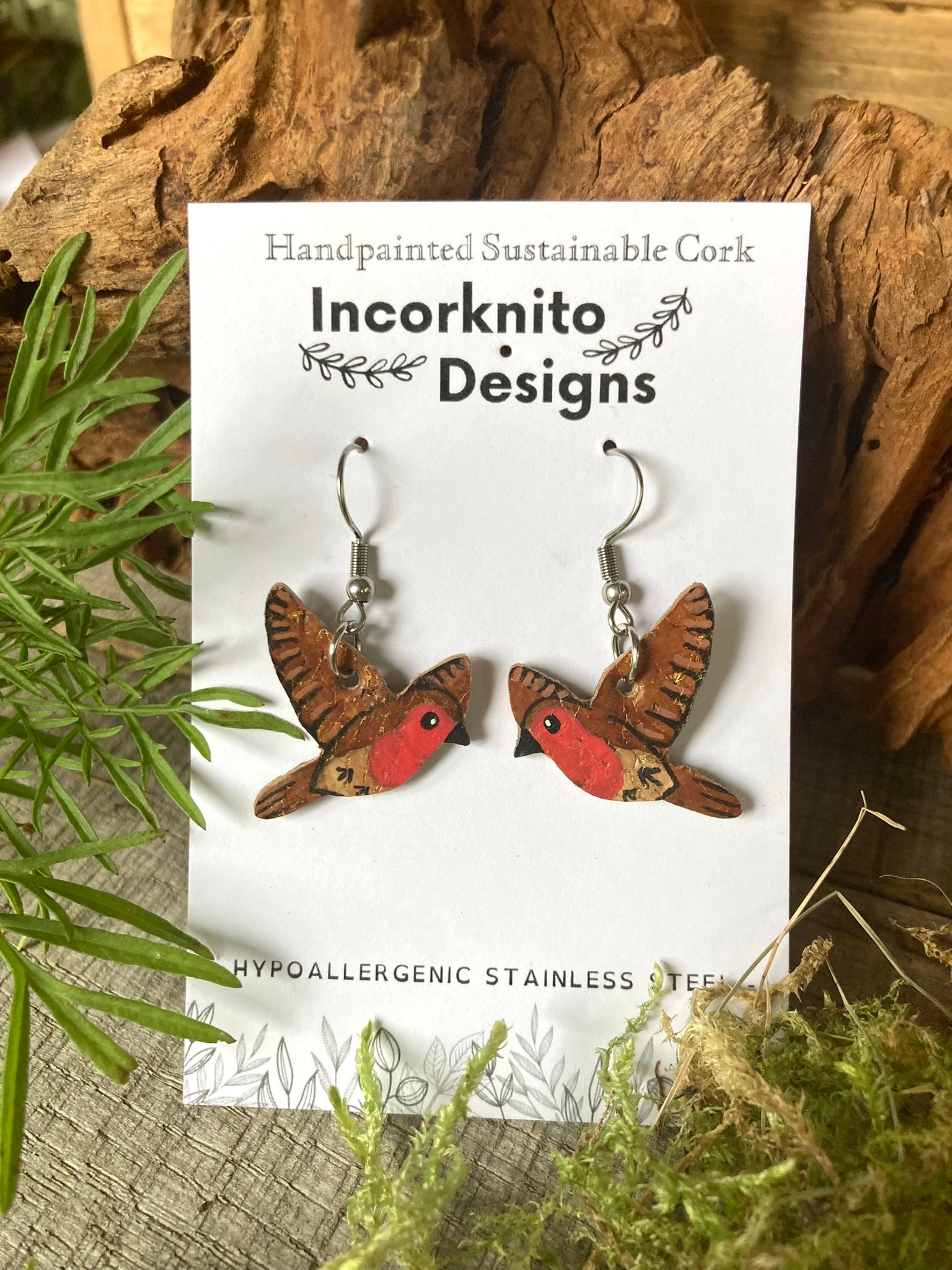 Flying robin cork earrings on silver hooks on Incorknito Designs branded card with cork and moss background. Eco-friendly nature jewellery, handpainted in Suffolk, UK.